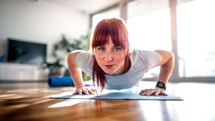 Micro-Workouts Frau macht im Wohnzimmer Liegestütze als Micro-Workout