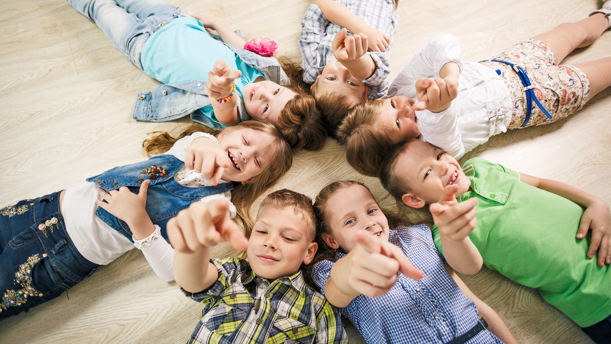 Kinderentwicklung Kinder schauen und zeigen nach oben in die Kamera