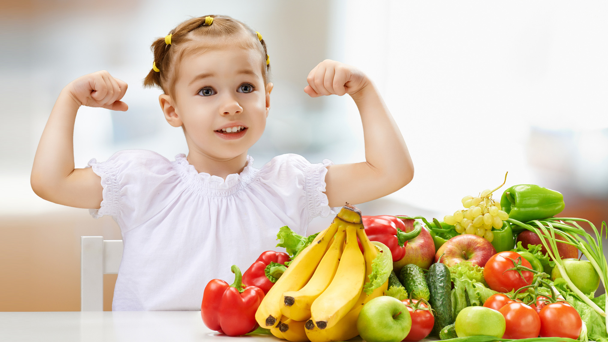 Obst & Gemüse Kind spannt die Arme an und steht vor Obst