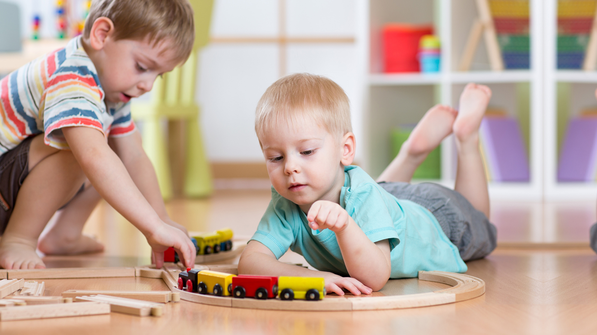 Spielend wachsen - Weltspieltag 2 Jungen spielen auf dem Fußboden mit einer Eisenbahn