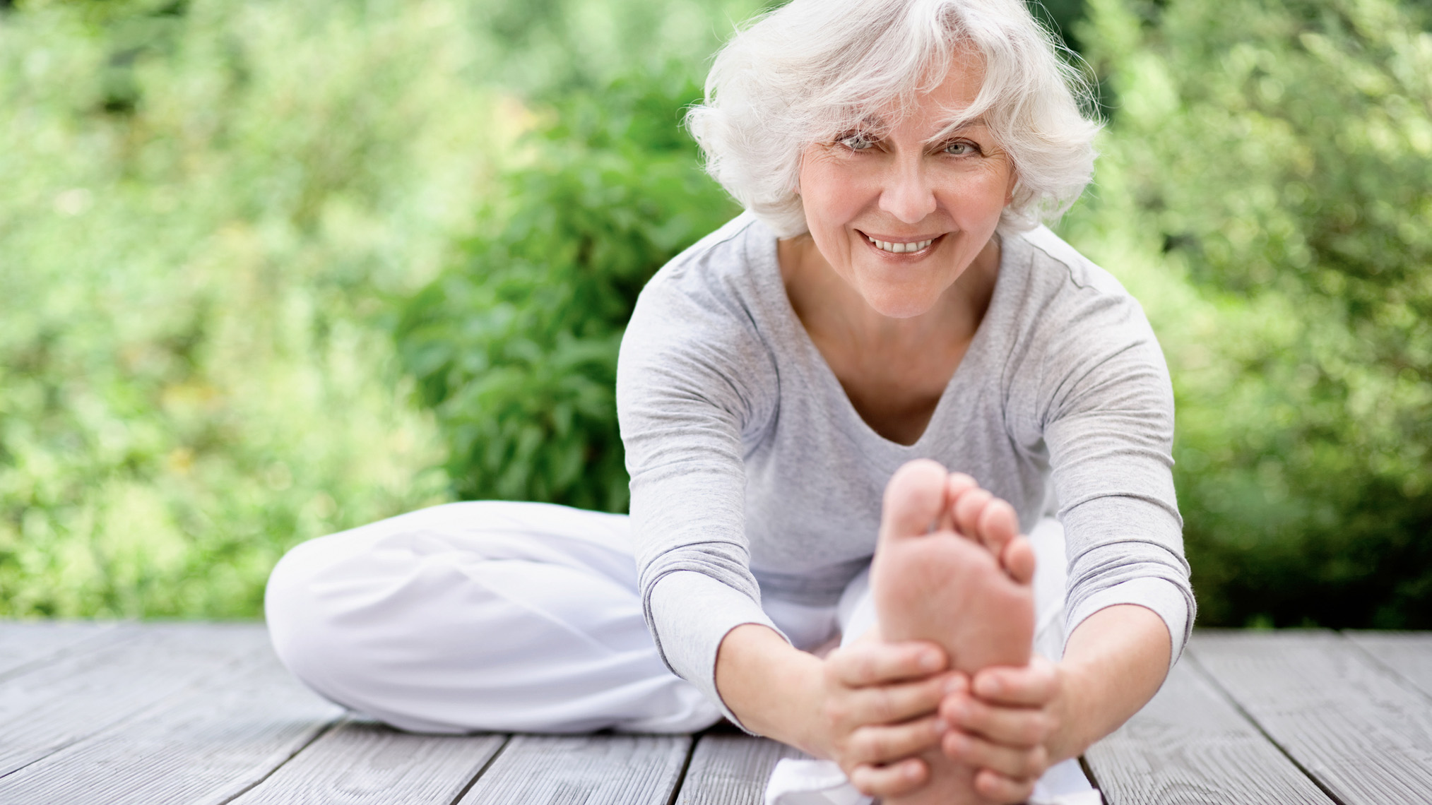 Disease Management Programme Sportliche Seniorin beim Streching im Freien