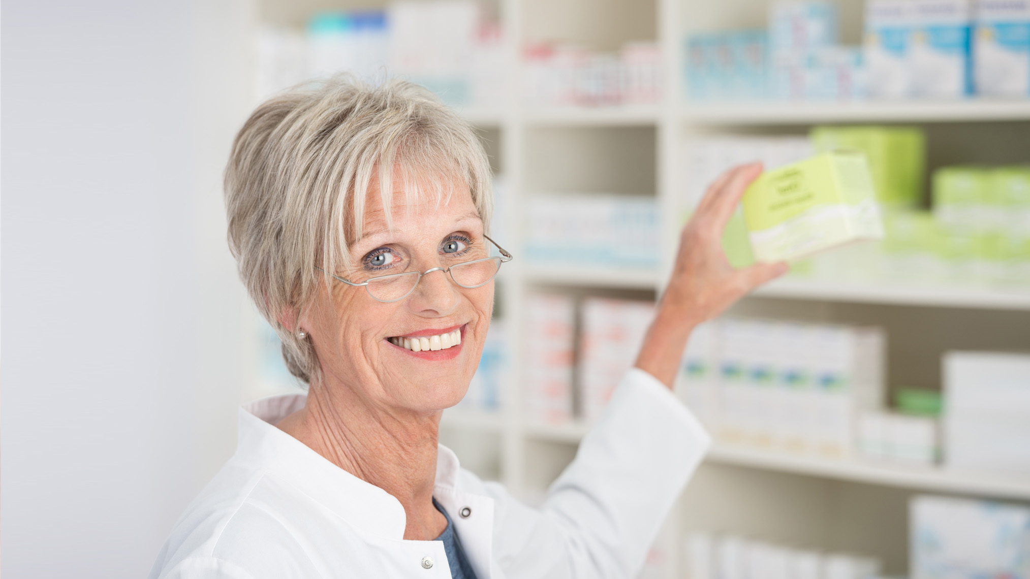Apothekensuche Ältere Apothekerin holt Medikamente aus dem Regal