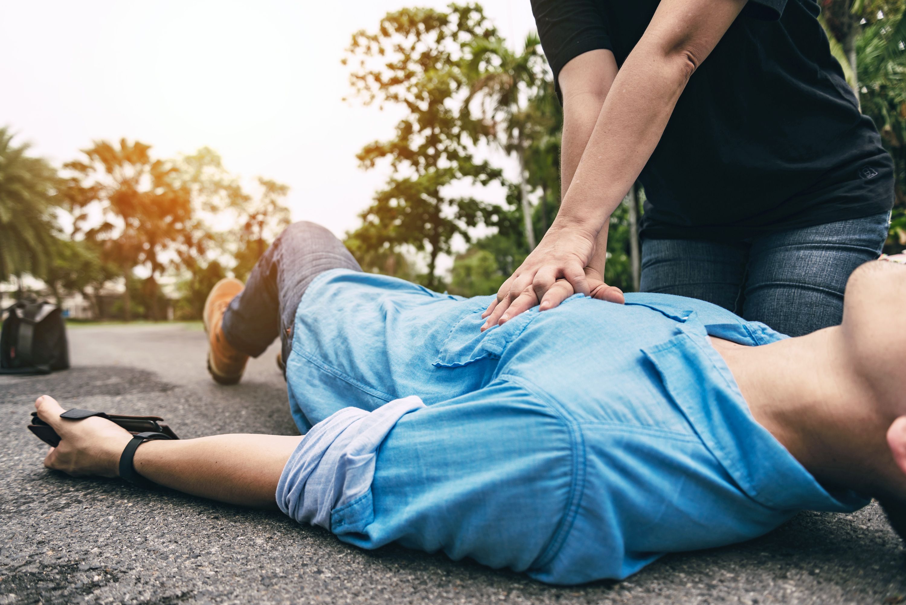 Erste Hilfe – Im Notfall keine Zeit verlieren Wiederbelebung mit Herzdruckmassage bei einem Mann, der auf der Straße liegt