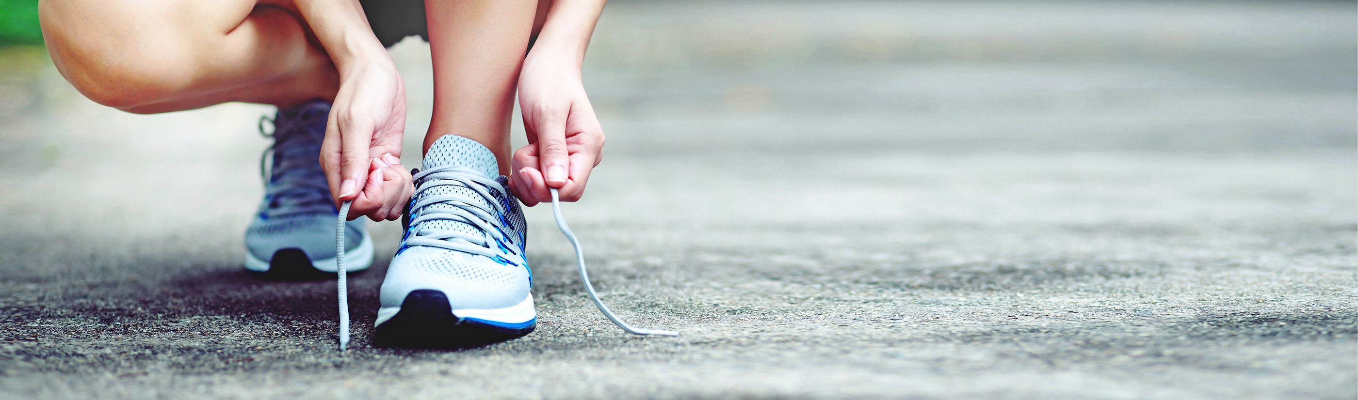 Laufen – Flexibler Ausdauersport Läuferin bindet die Schnürsenkel ihrer Laufschuhe zu