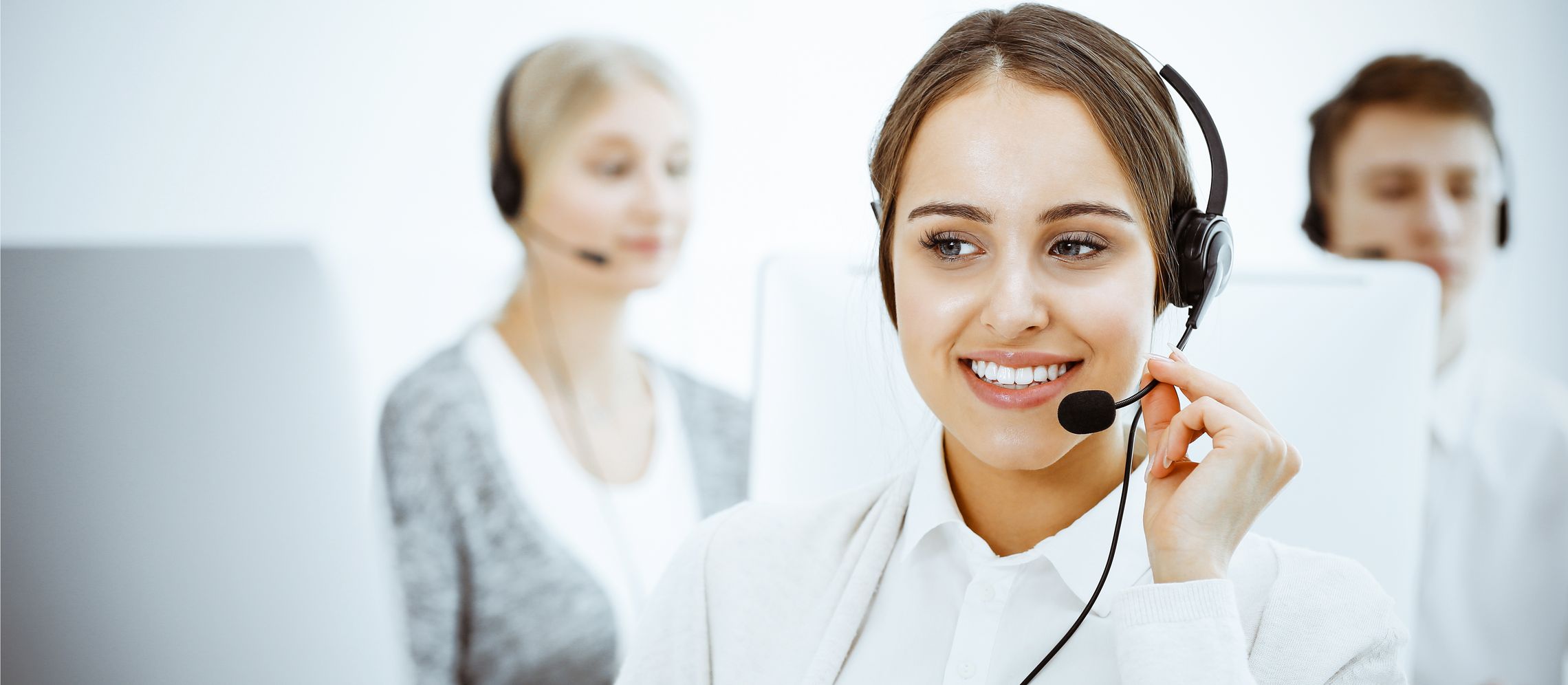 Kontaktmöglichkeiten zur IKK gesund plus Junge Mitarbeiterin mit einem Headset führt gerade ein Telefongespräch
